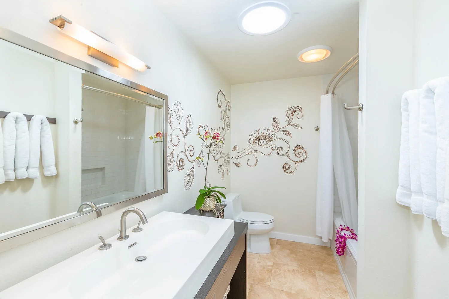 A bright bathroom with a wide sink, wall decorations, and a shower.