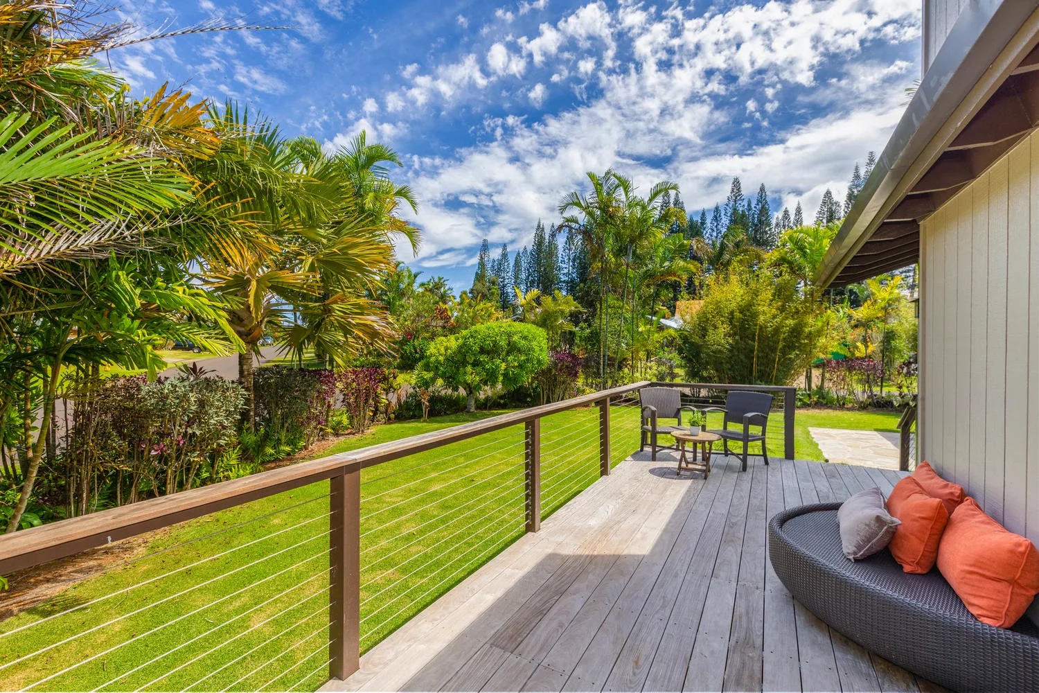 Outdoor deck seating overlooks a green lawn and lush garden.