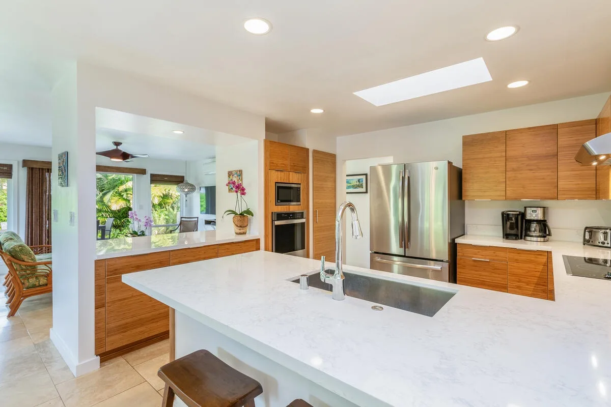 A bright kitchen features a large island with a sink and stainless steel appliances.