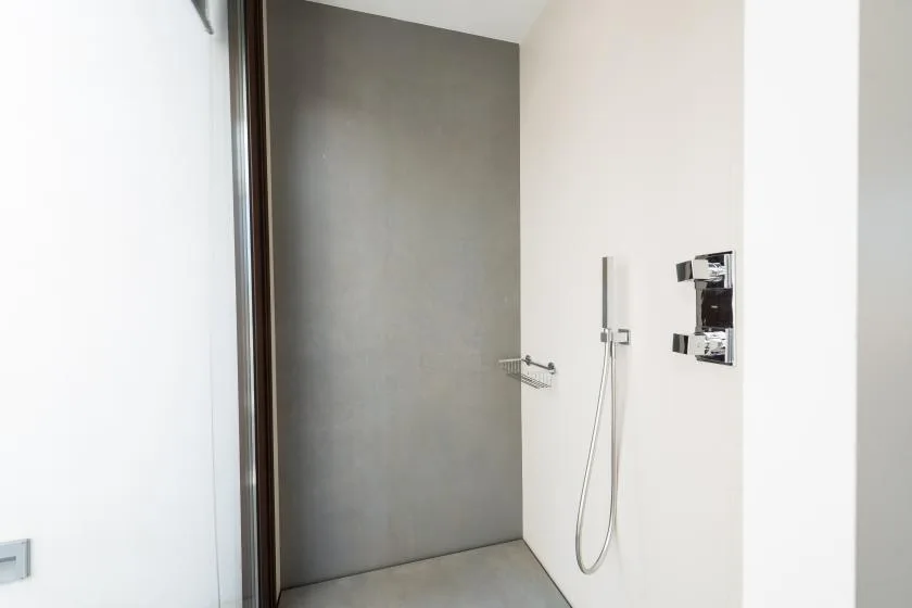 A modern shower area with a handheld shower fixture and gray wall.