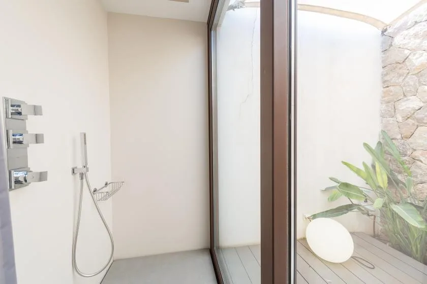 A modern shower area opens onto a small patio with plants.