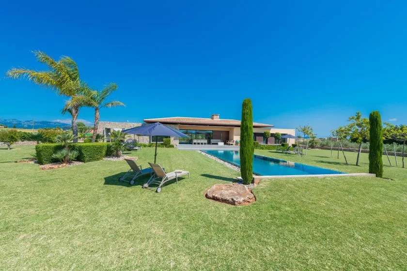 A landscaped outdoor pool area with lounge seating and a modern building beyond.