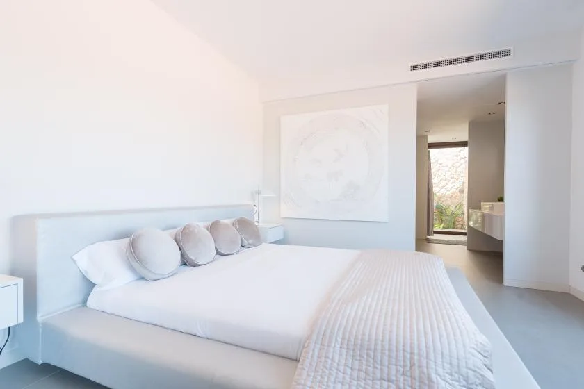 A bright bedroom with a large bed and pale wall art.