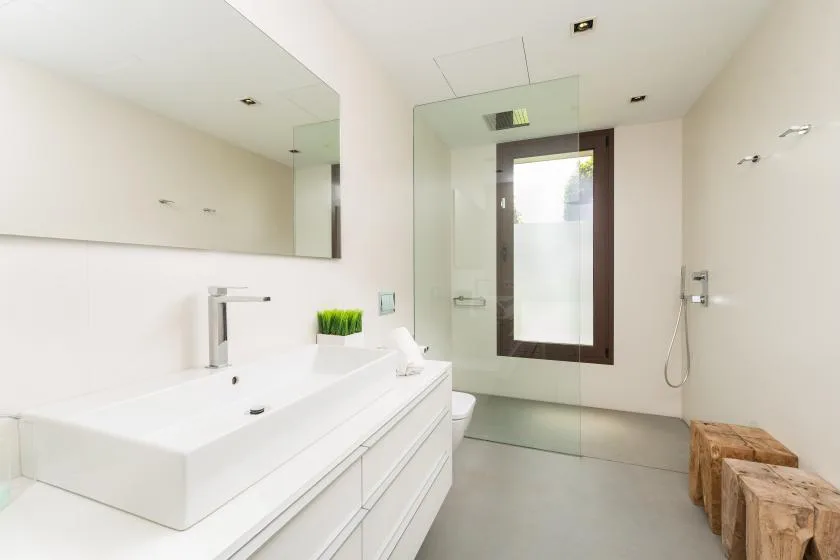 A bright modern bathroom with a long vanity, large mirror, and shower.
