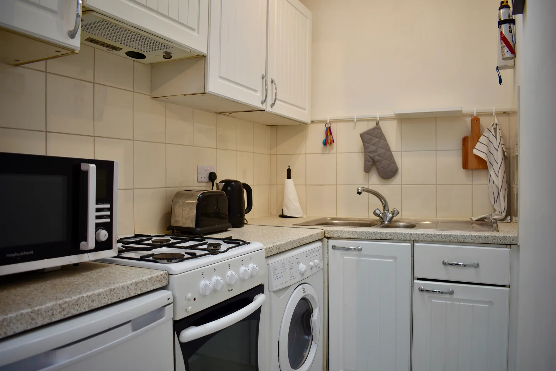 Una cocina compacta con estufa, lavadora y fregadero.