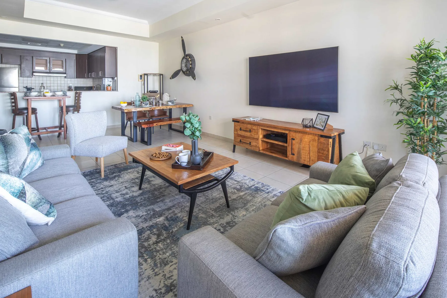 Una sala de estar con asientos, una mesa de centro y un televisor sobre un mueble de madera.