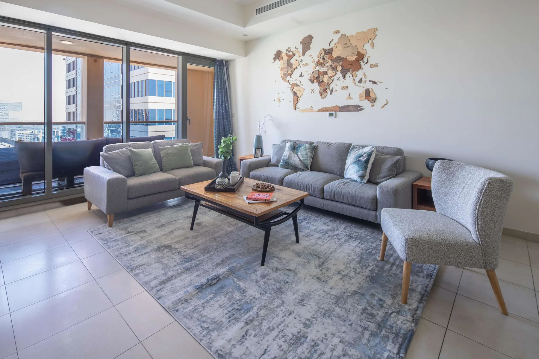 Una sala de estar luminosa con asientos alrededor de una mesa de centro junto a grandes ventanas.