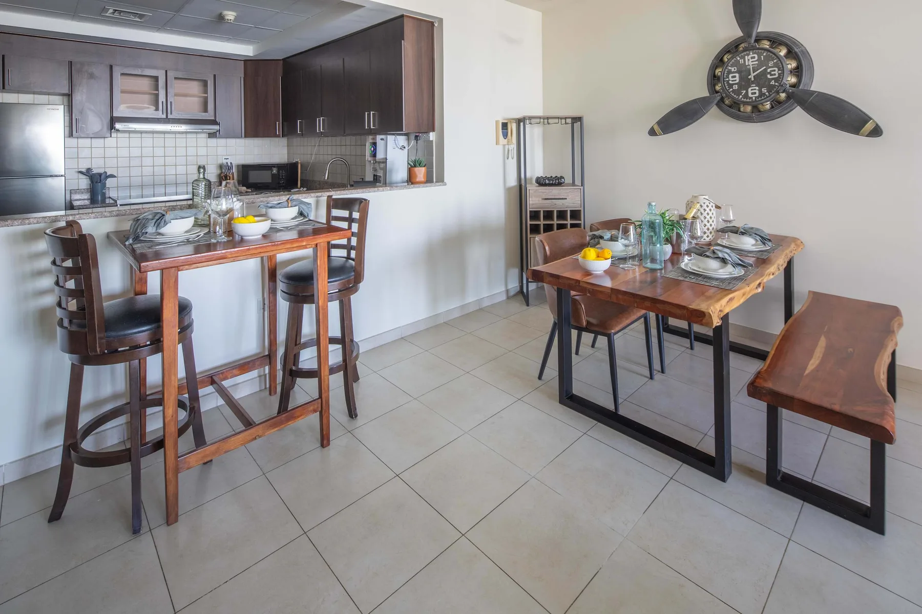 Un comedor con dos mesas dispuestas junto a una cocina abierta.