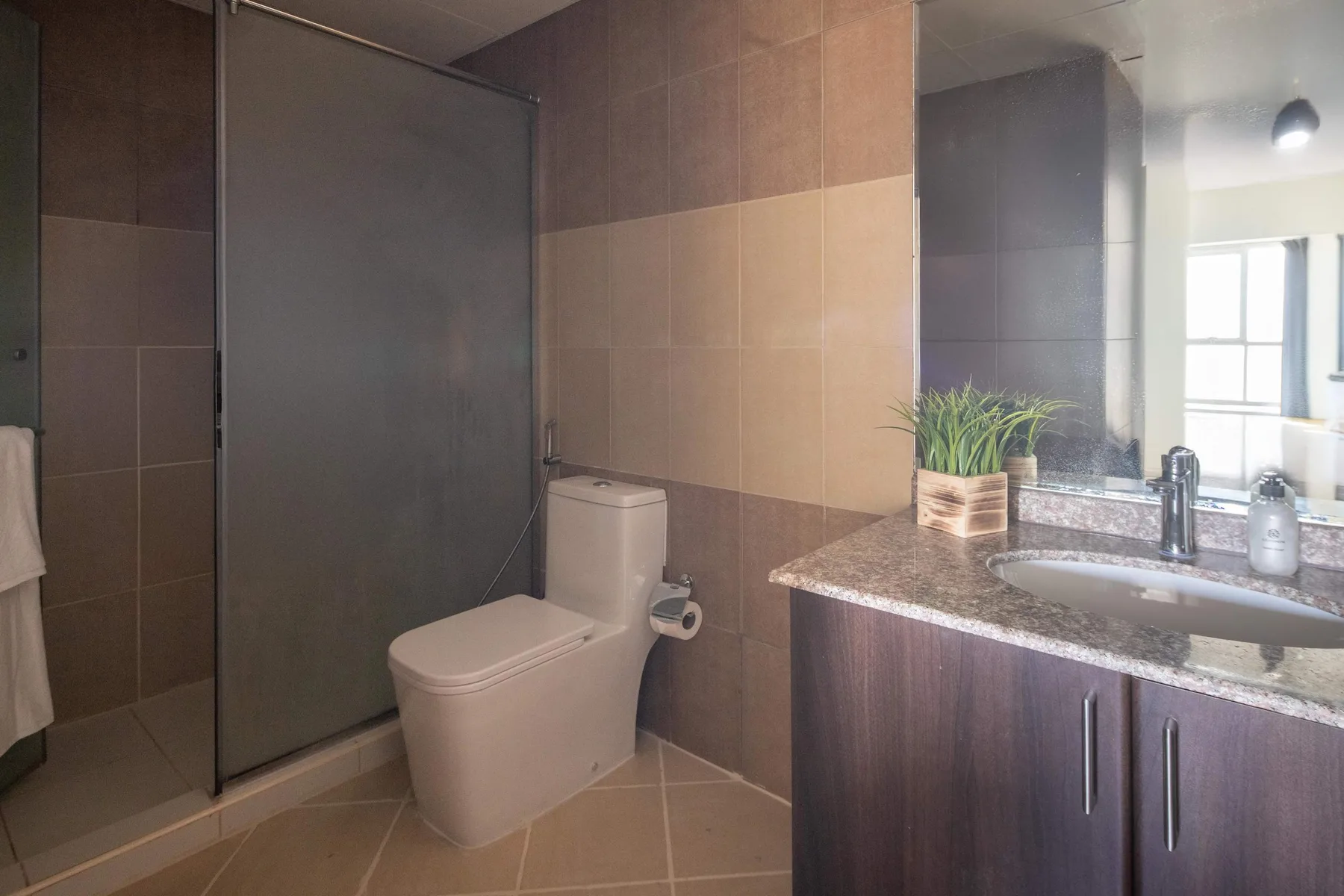 Un baño con azulejos, inodoro, ducha y mueble con lavabo.