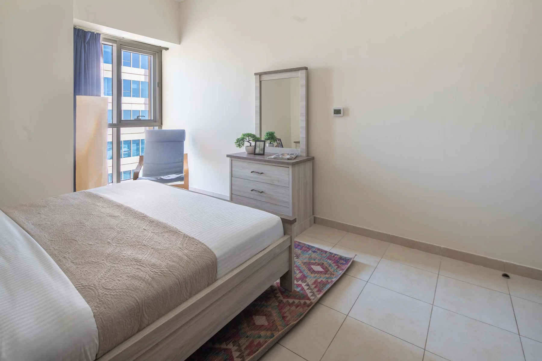 Un dormitorio con una cama, una cómoda y una ventana.