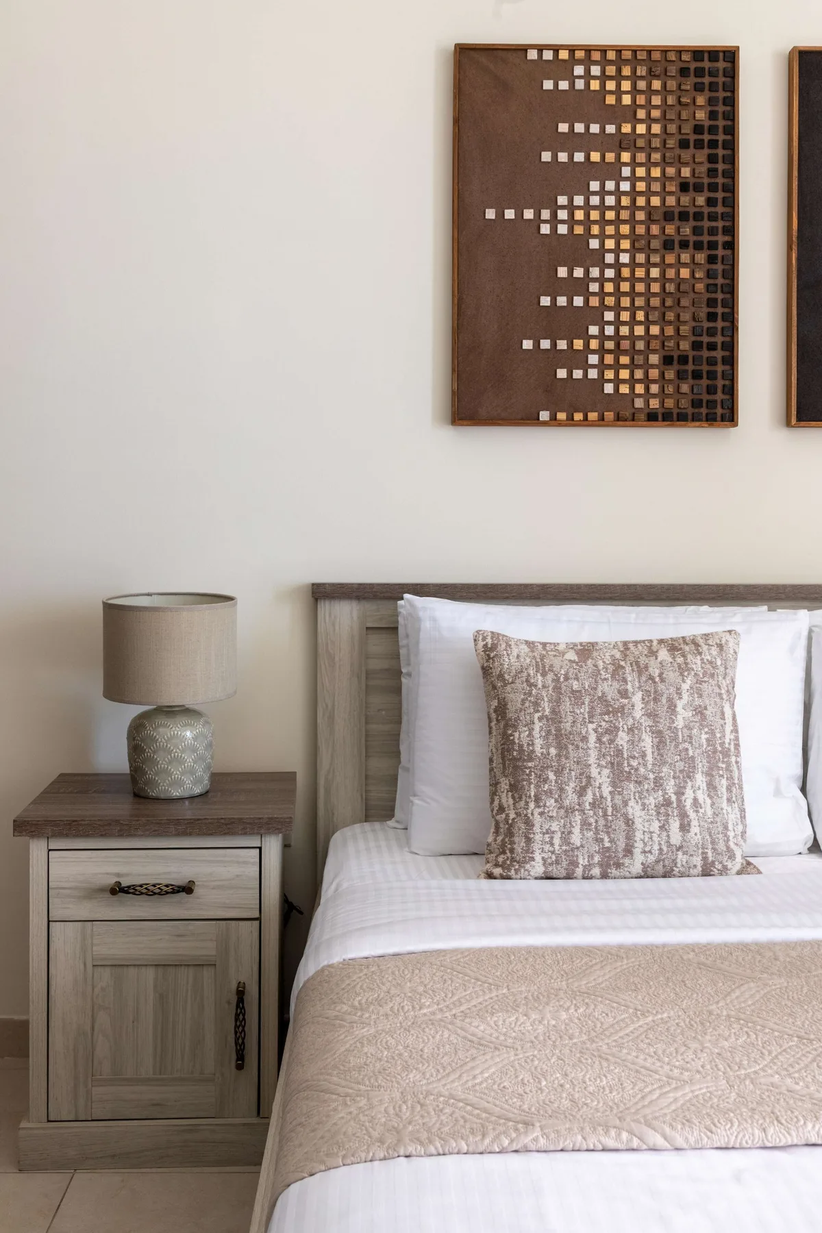 Un dormitorio con una cama bien tendida y una mesita de noche de madera.