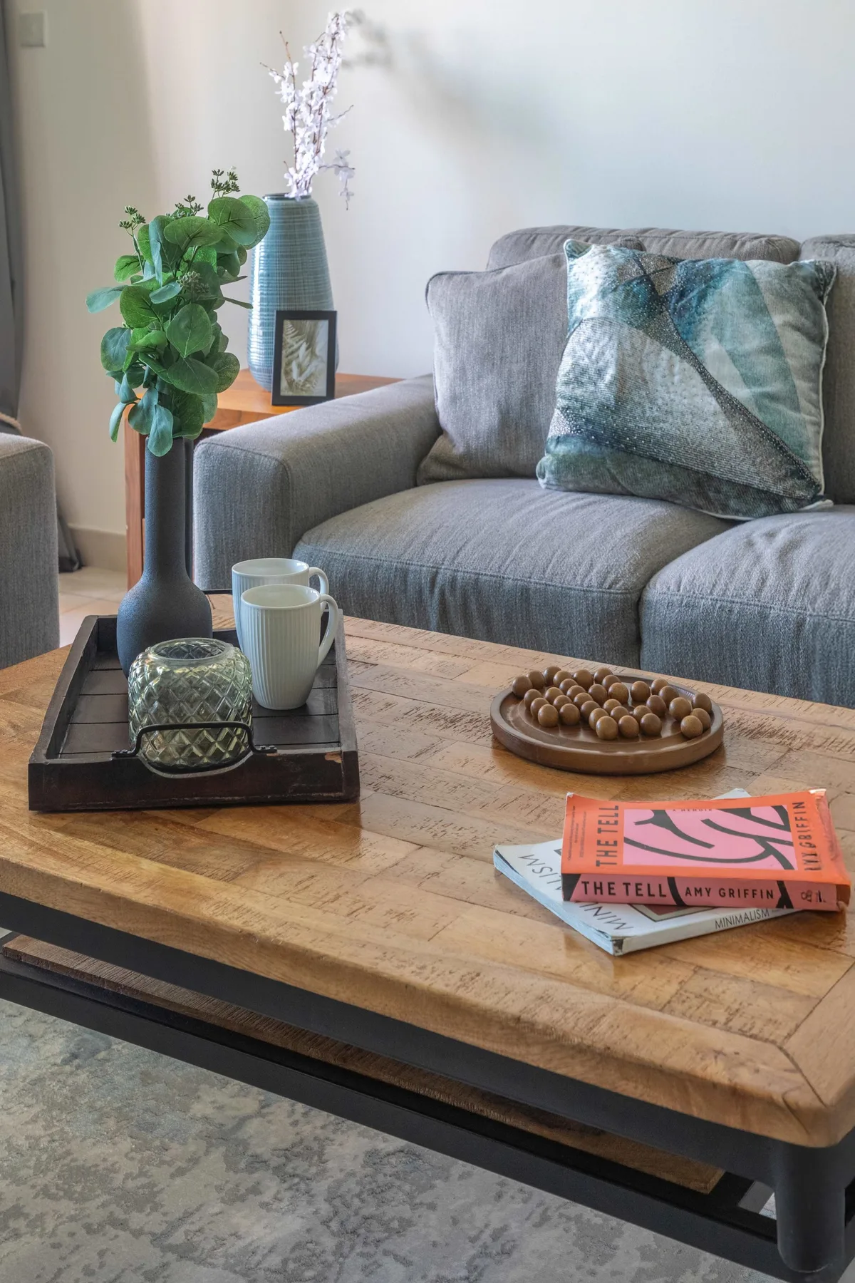 Una sala de estar con un sofá gris y una mesa de centro de madera.