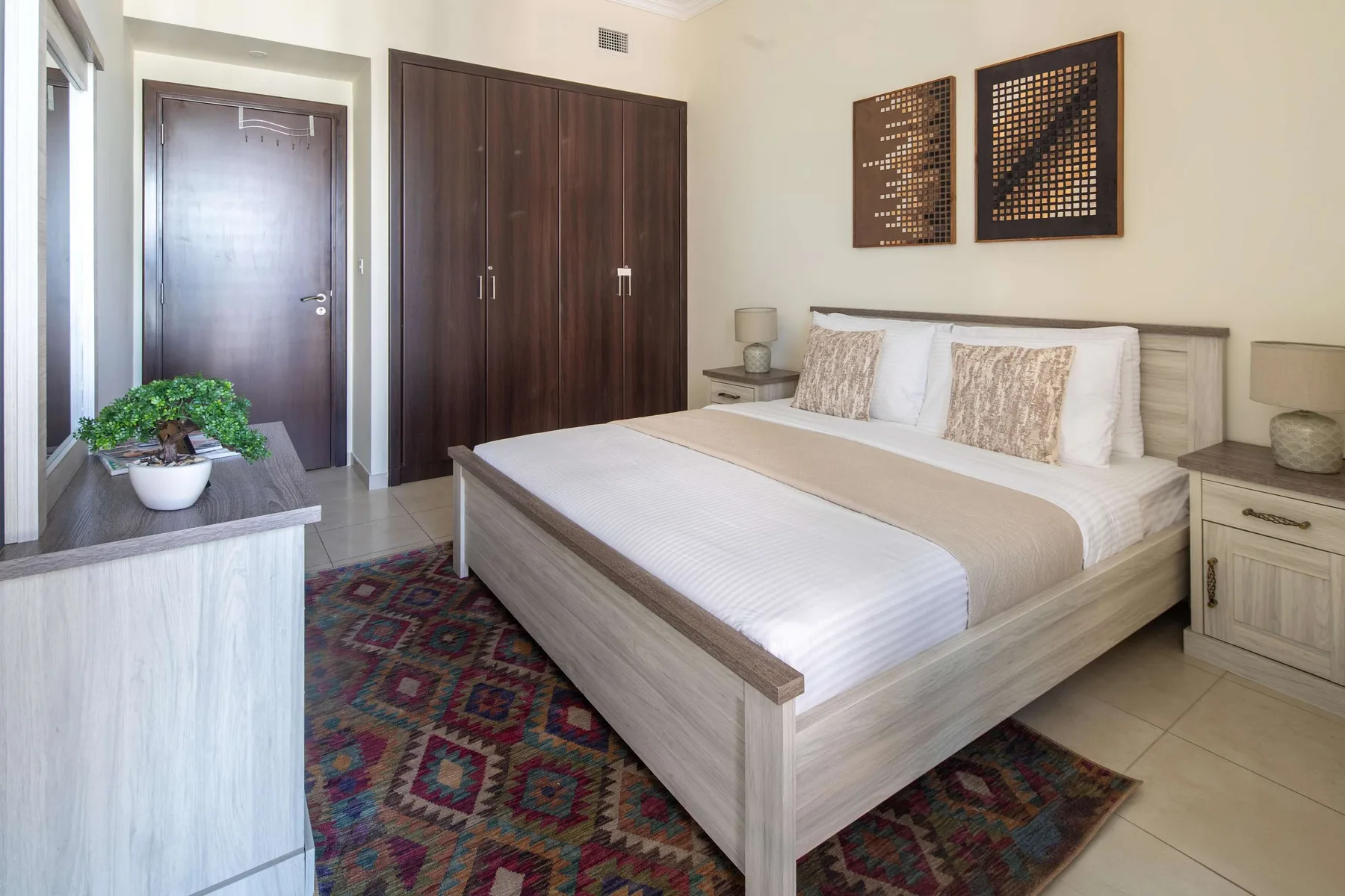 Un dormitorio con una cama grande, un armario oscuro y una alfombra colorida.