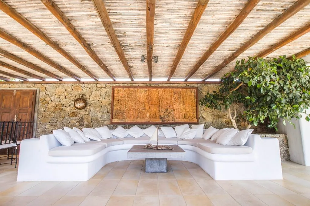 A covered lounge with white seating arranged around a low table.