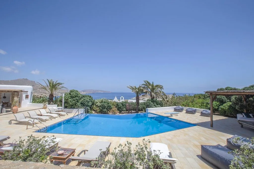 A swimming pool overlooks the sea, with sun loungers on the surrounding terrace.