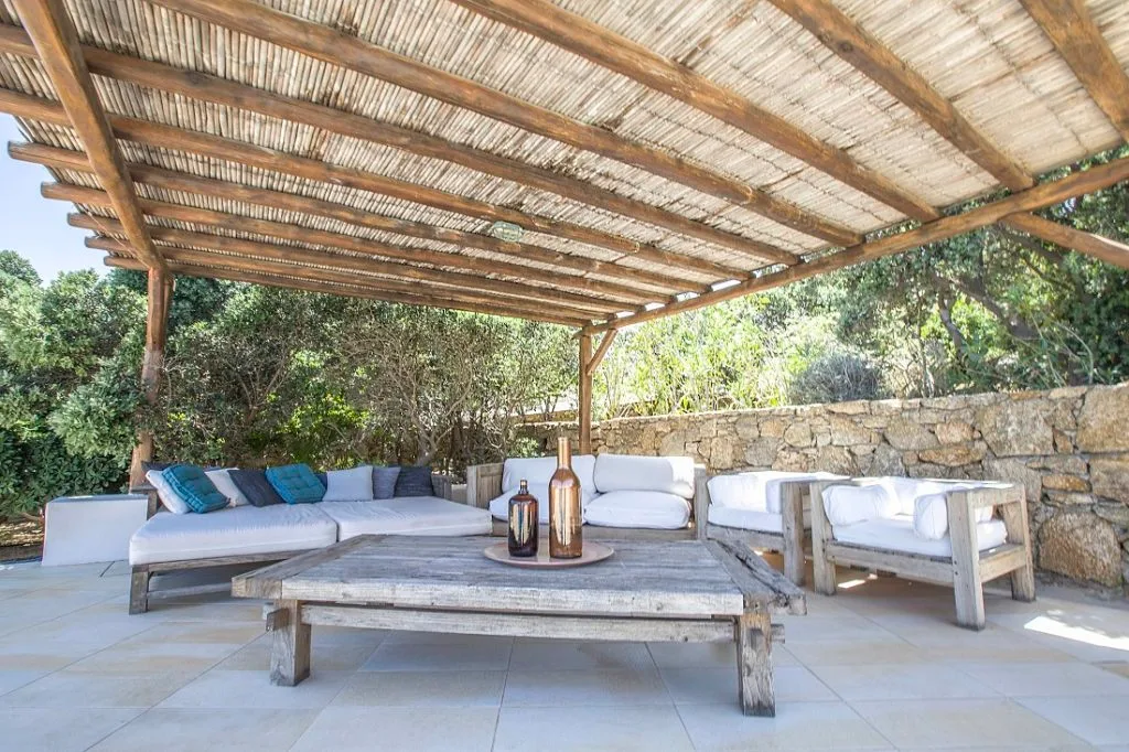 An outdoor seating area under a rustic canopy, with a low table.