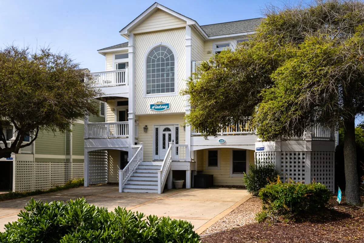Una casa elevada con una escalera central y árboles alrededor.