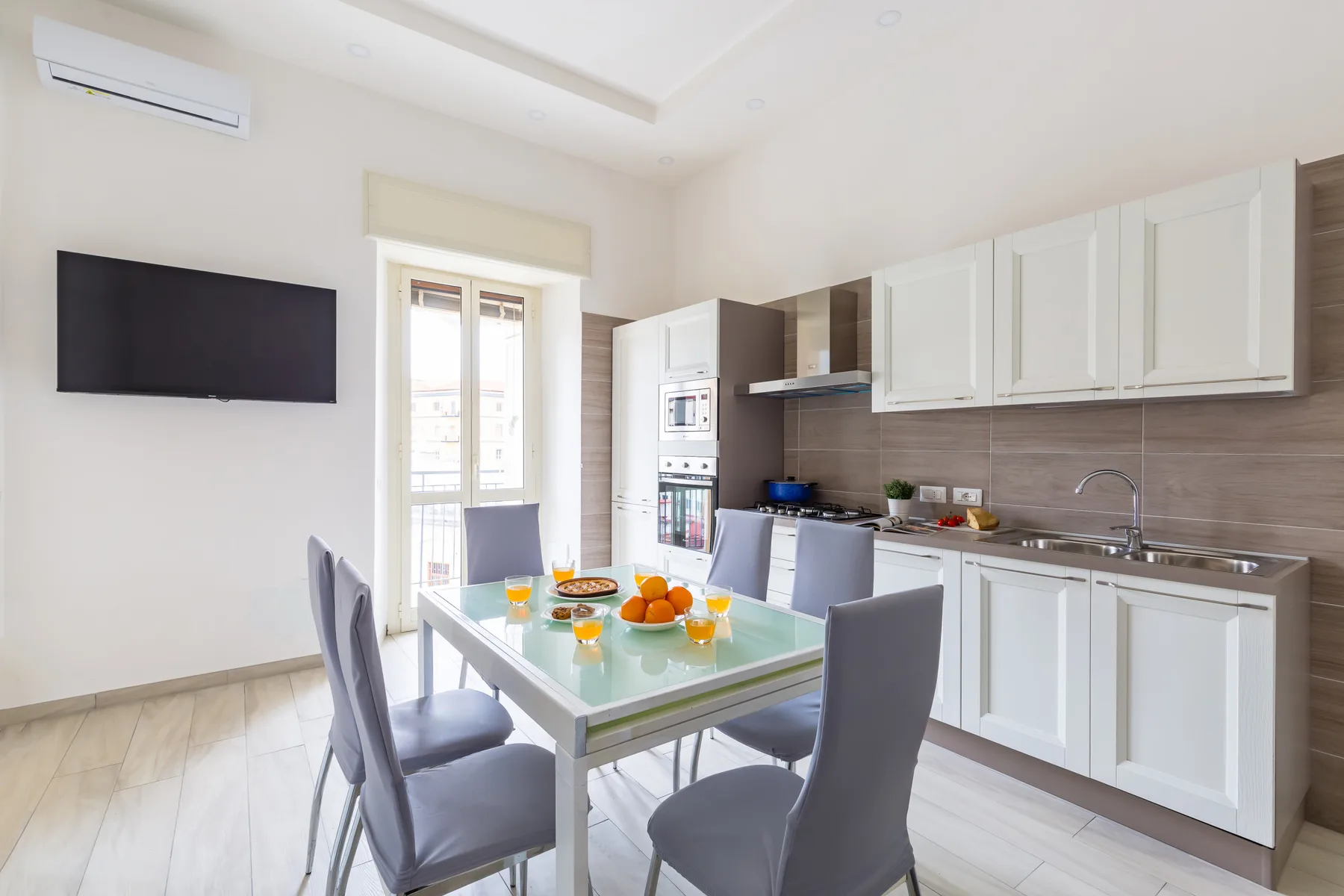 A bright kitchen and dining area with a table set in front of white cabinets.
