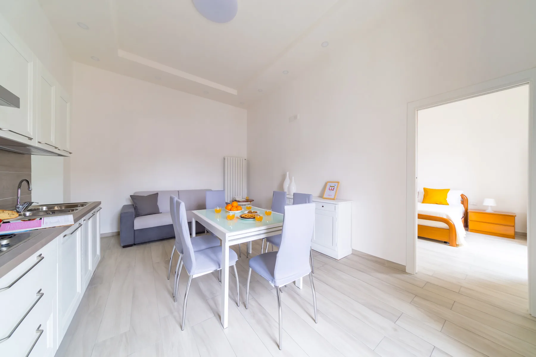 A bright dining area with a table and chairs beside a compact kitchen.