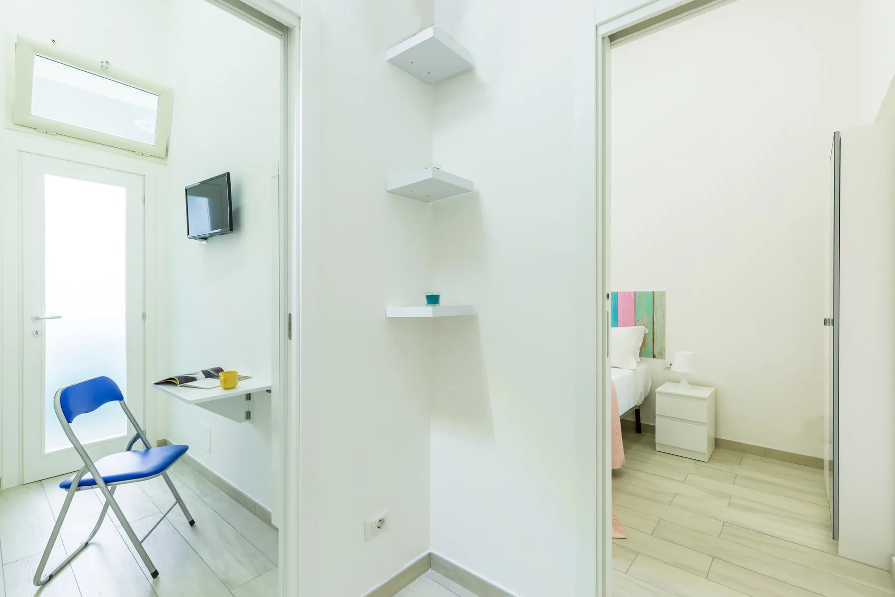 A bright interior hallway with wall shelves and open doorways.