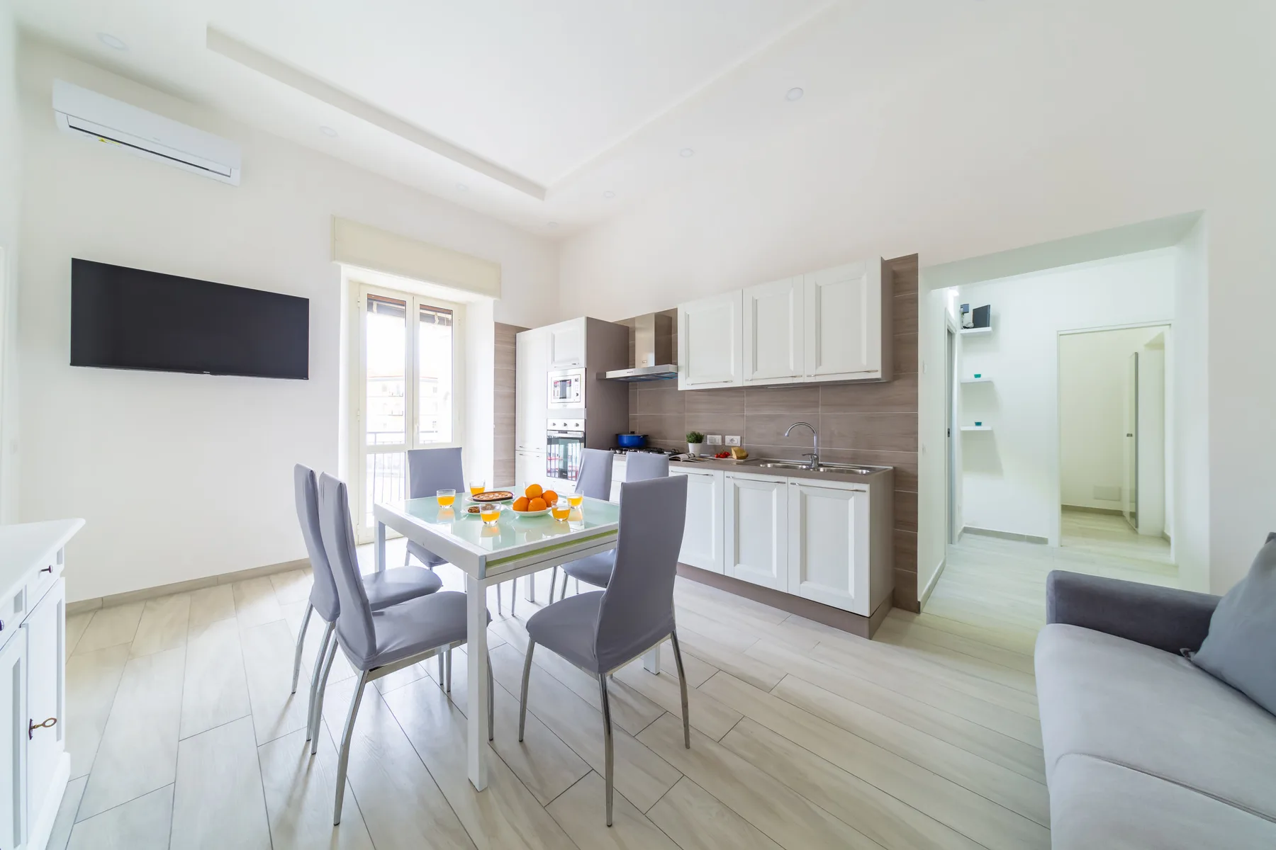 A bright kitchen and dining area with a table, seating, and white cabinets.