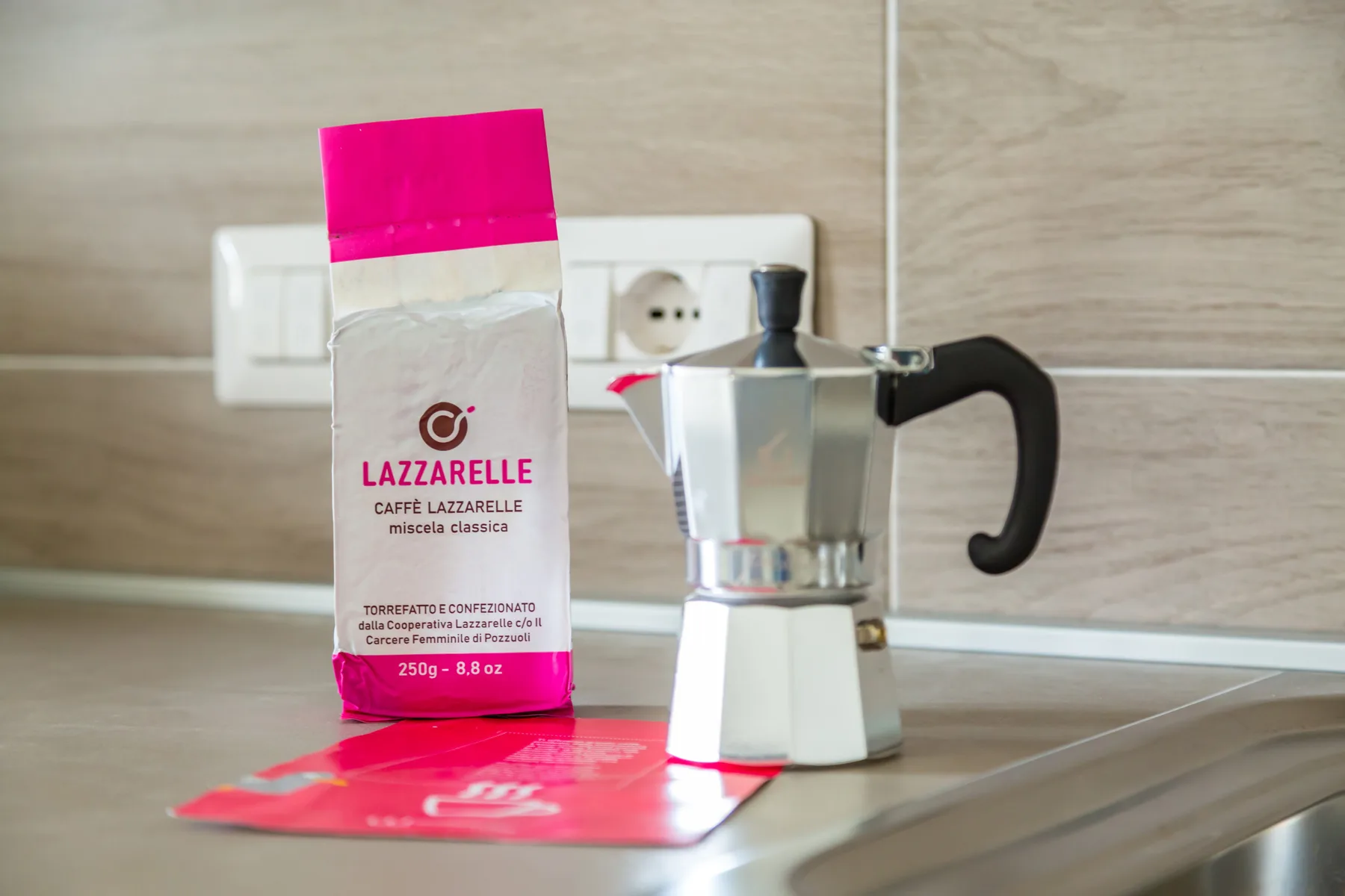 A stovetop coffee maker and coffee package sit on a kitchen counter.