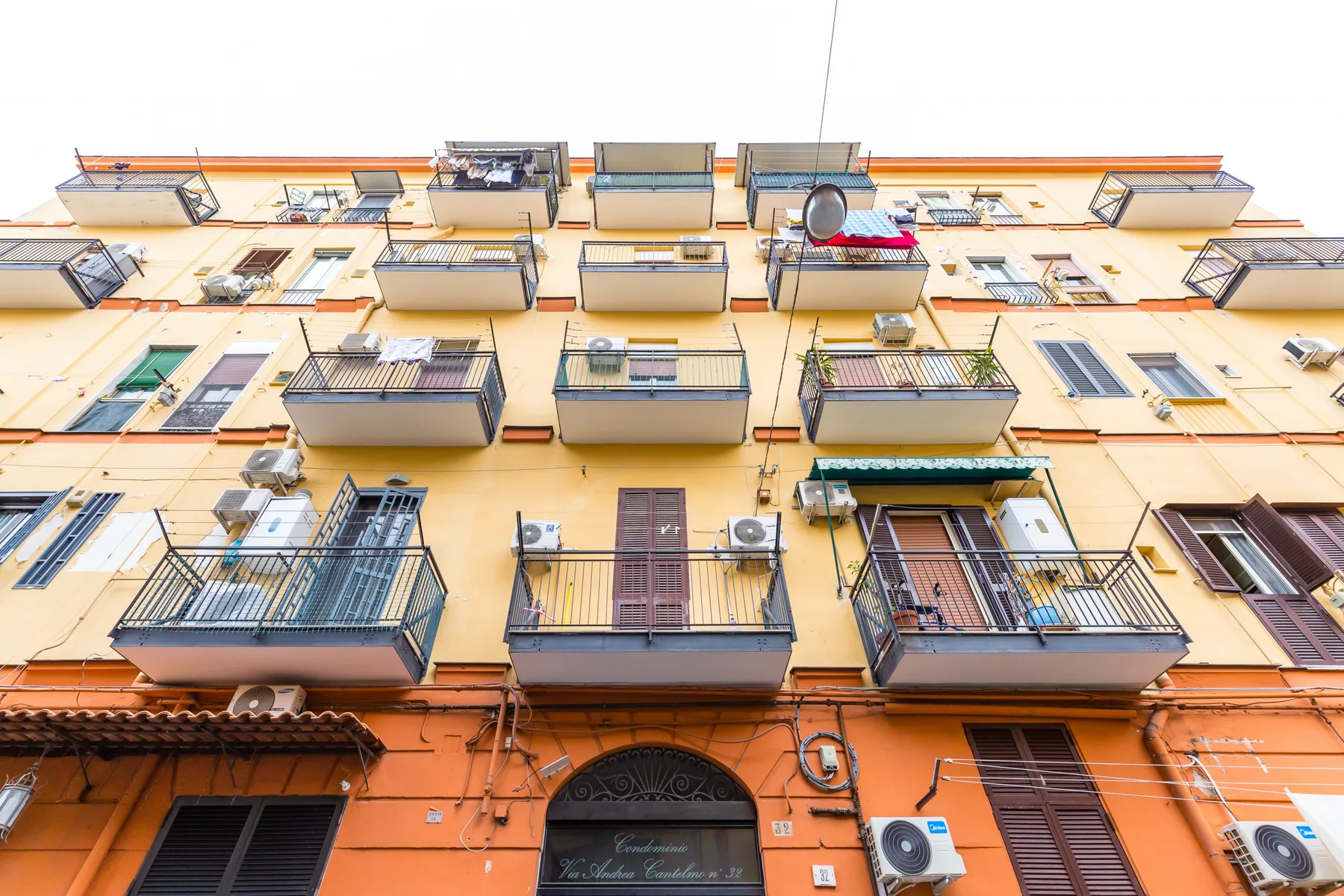 An upward view of a multistory apartment building with balconies and windows.
