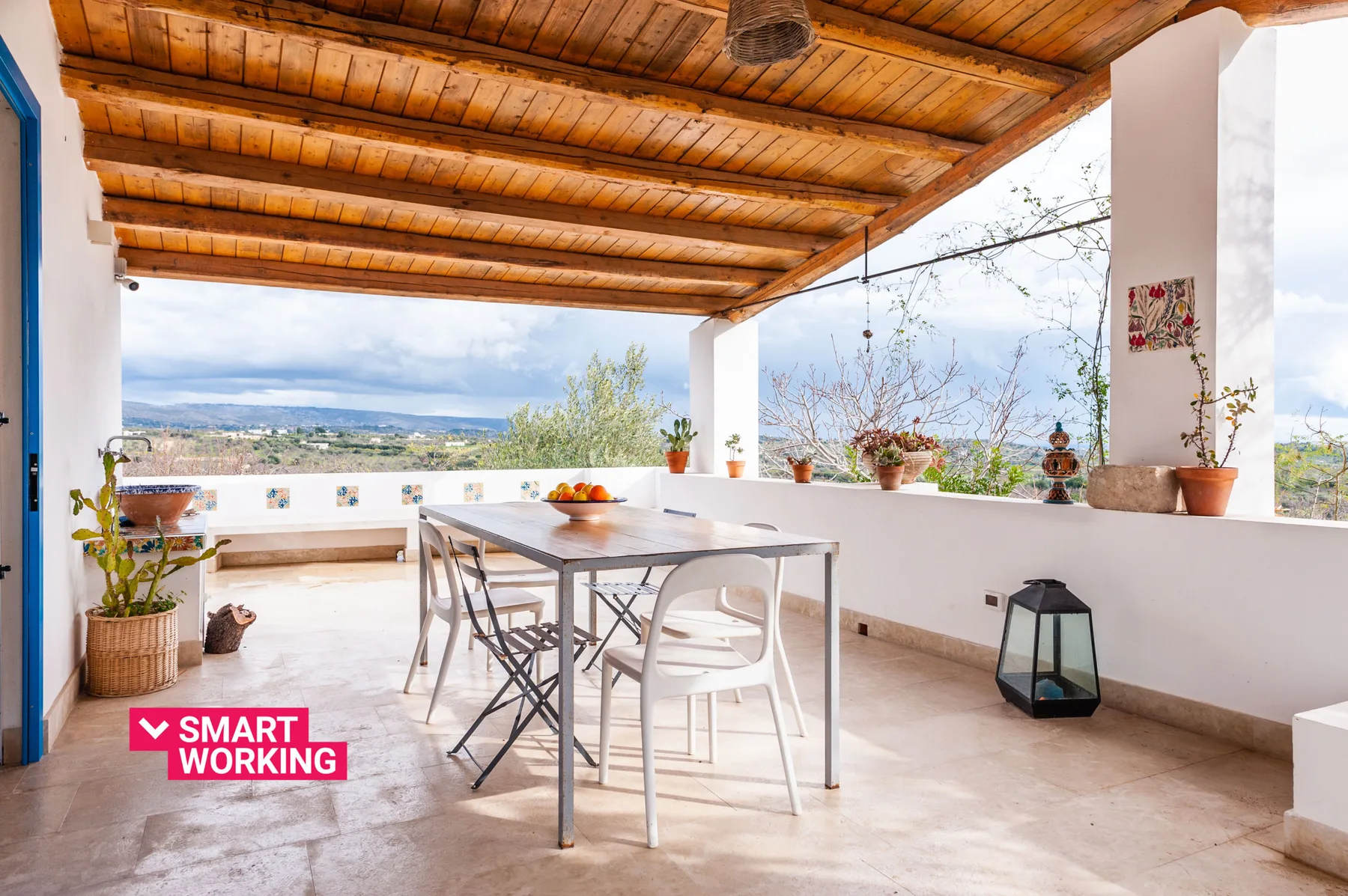 A covered terrace with a dining table and an open view of the landscape.