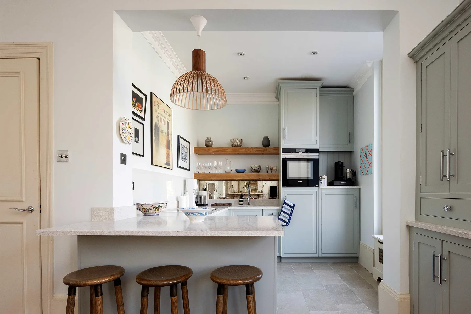 A bright kitchen with a central island and wooden stools.