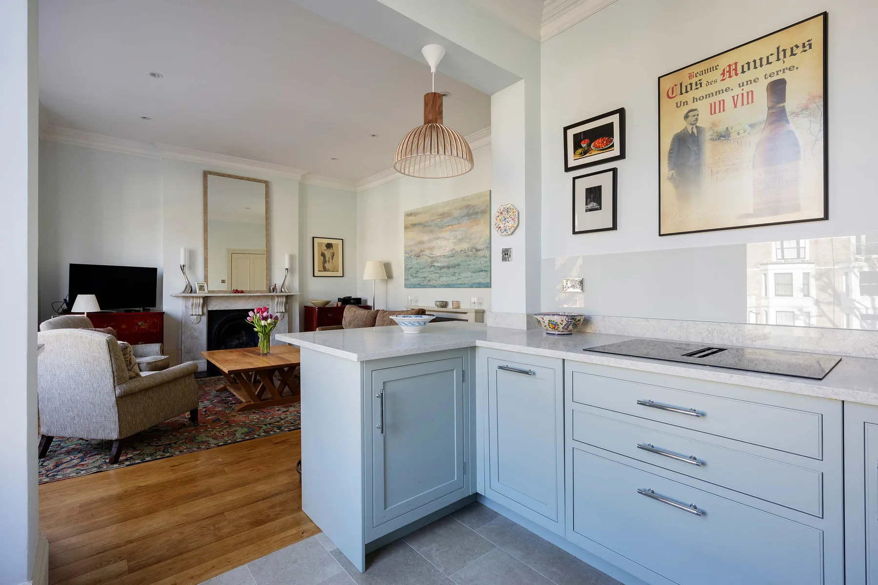 An open-plan kitchen and living area with pale cabinetry and a seating space.