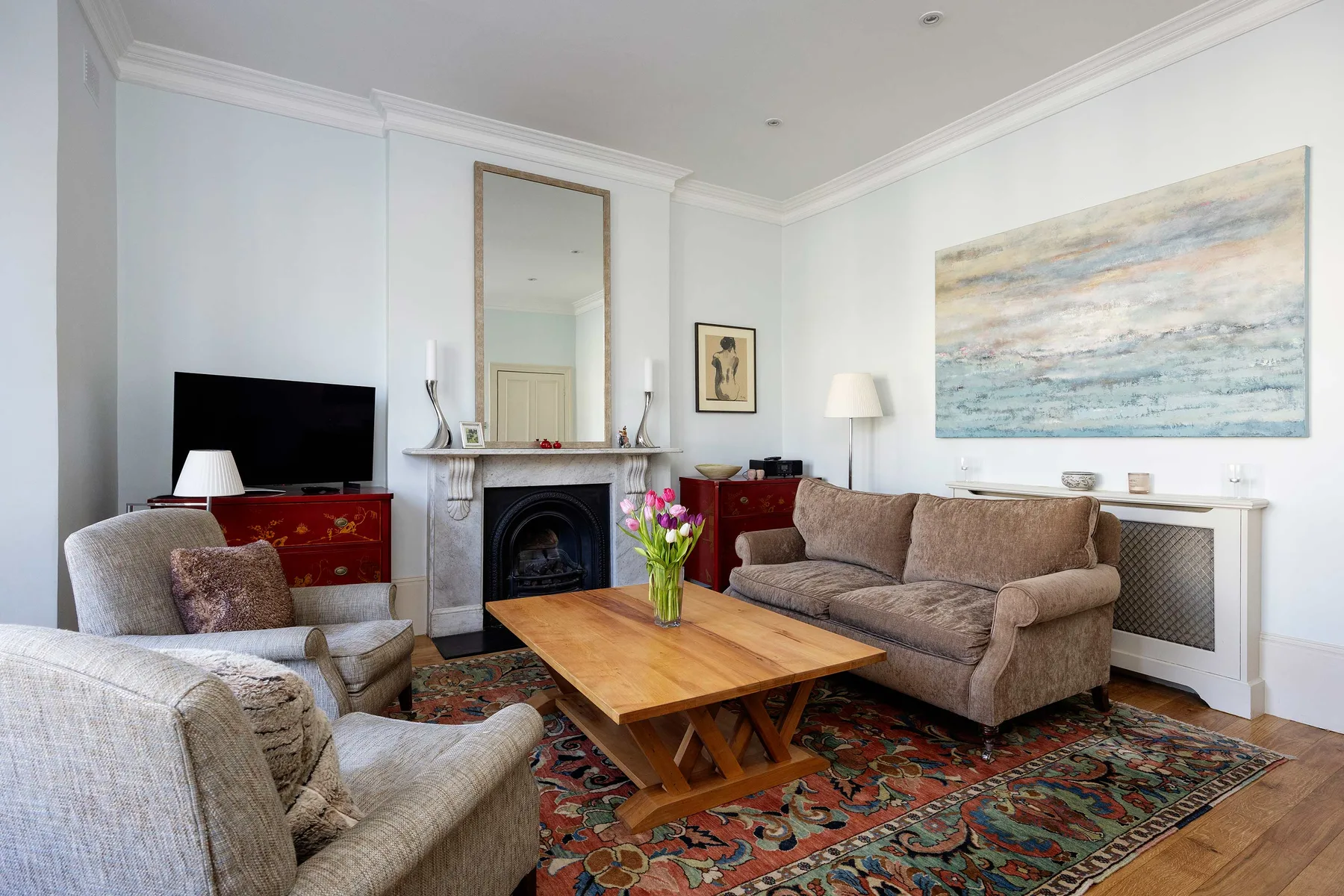 A living room with upholstered seating around a wooden coffee table and fireplace.