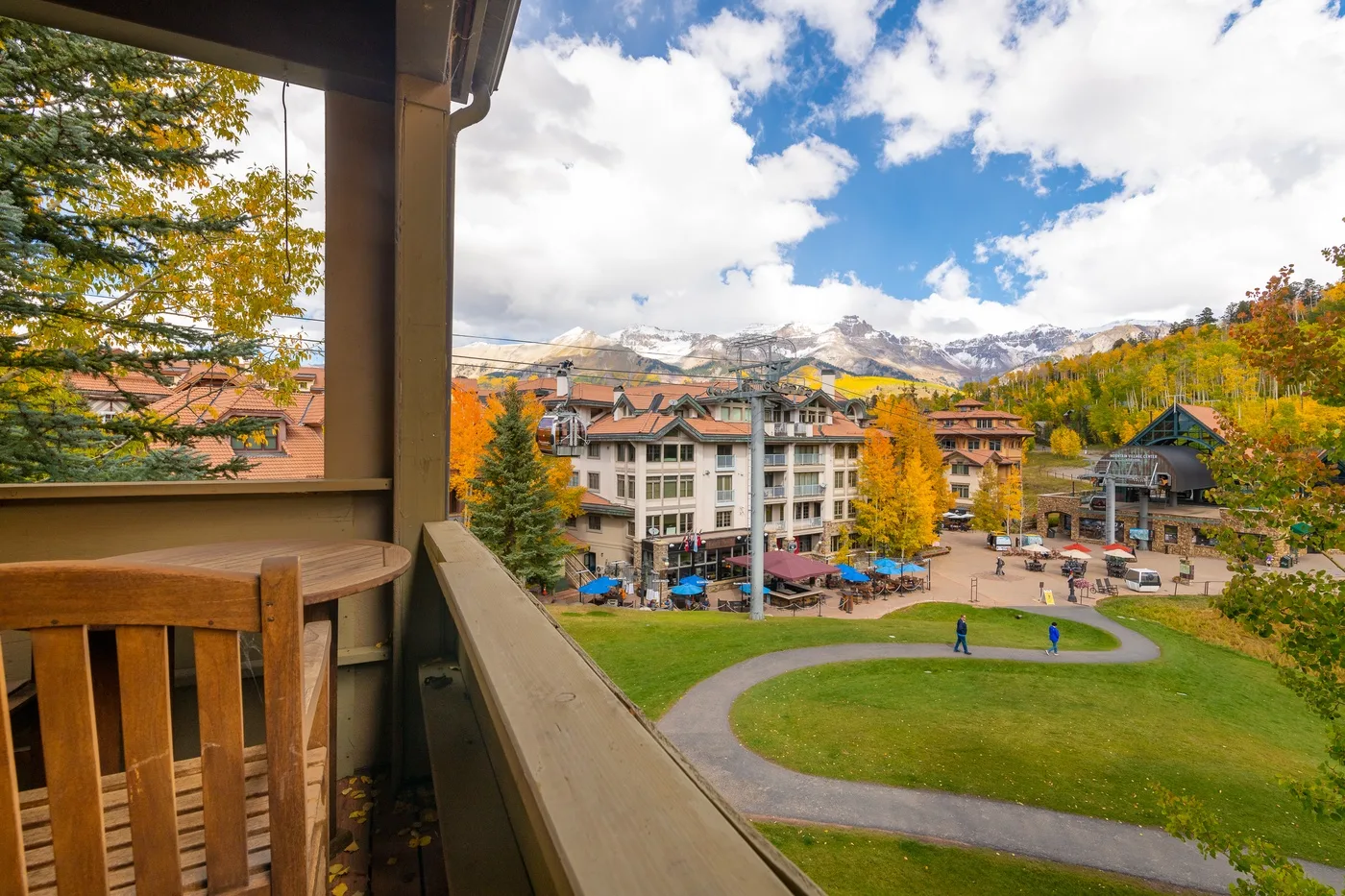 A balcony overlooks a landscaped courtyard, nearby buildings, and autumn-colored trees.