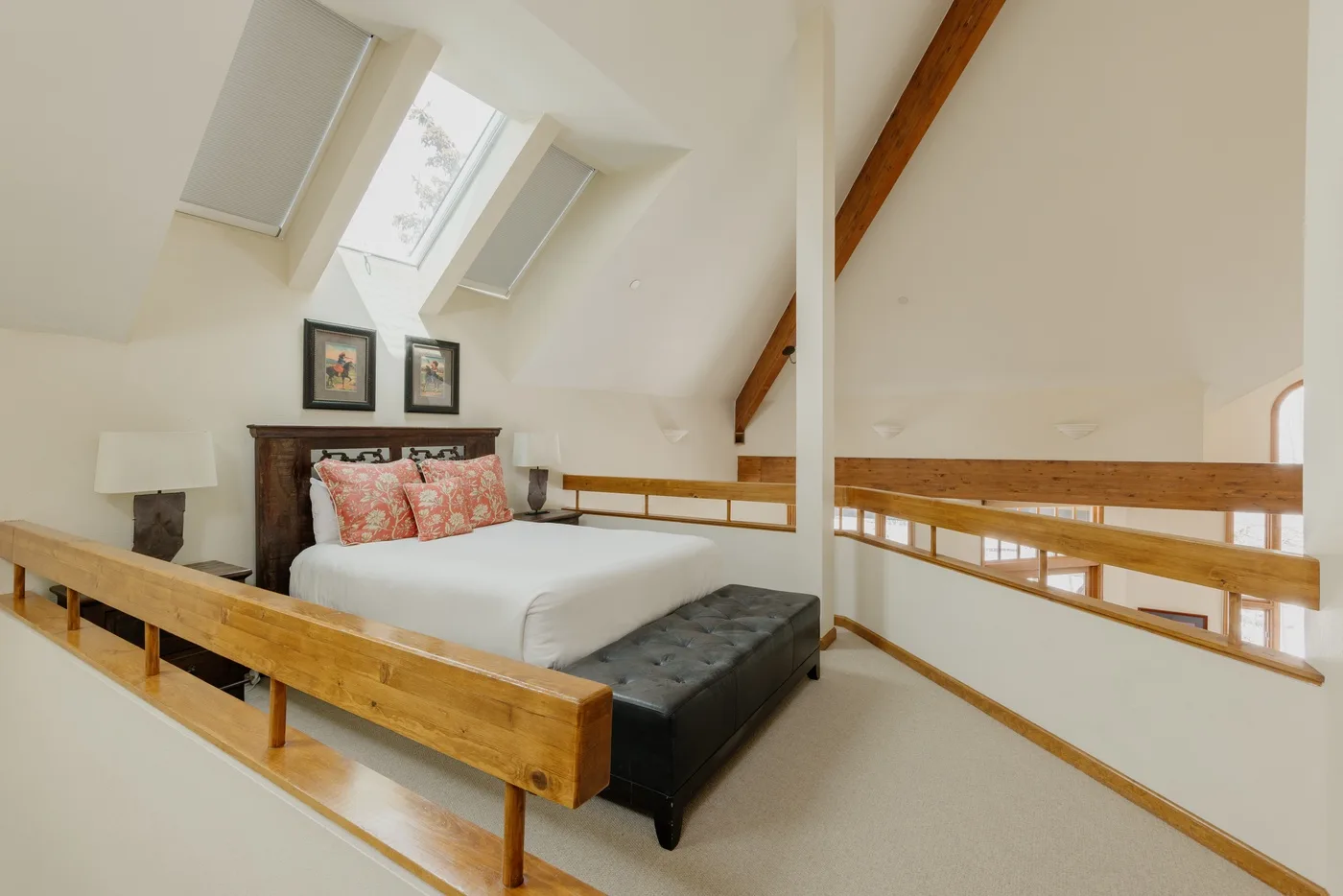 A bright loft bedroom with a bed beneath sloped ceilings and skylights.