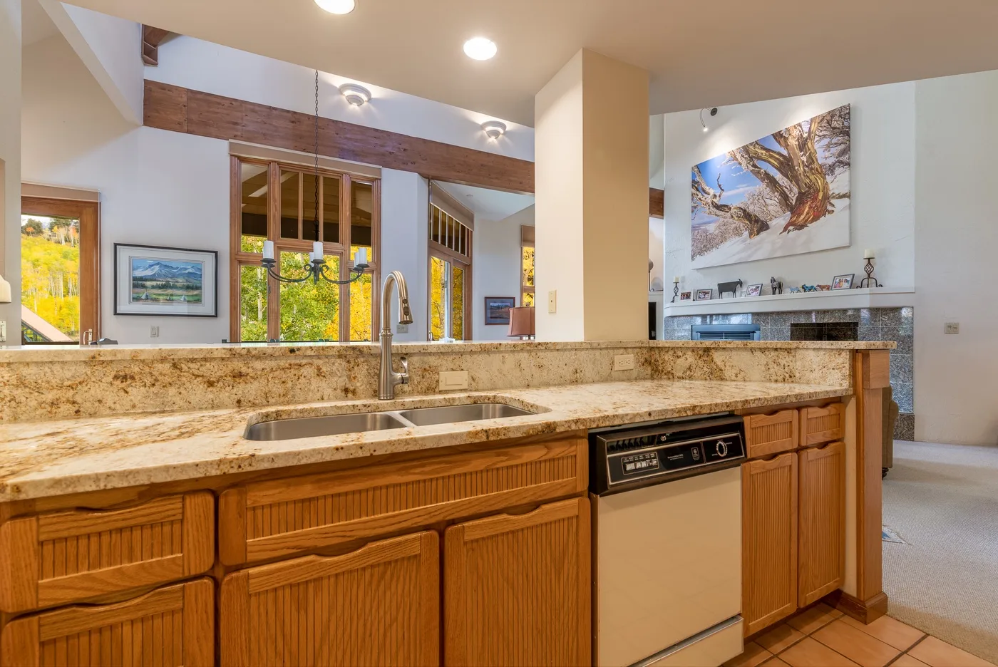 A bright kitchen with a long stone countertop and wooden cabinetry.