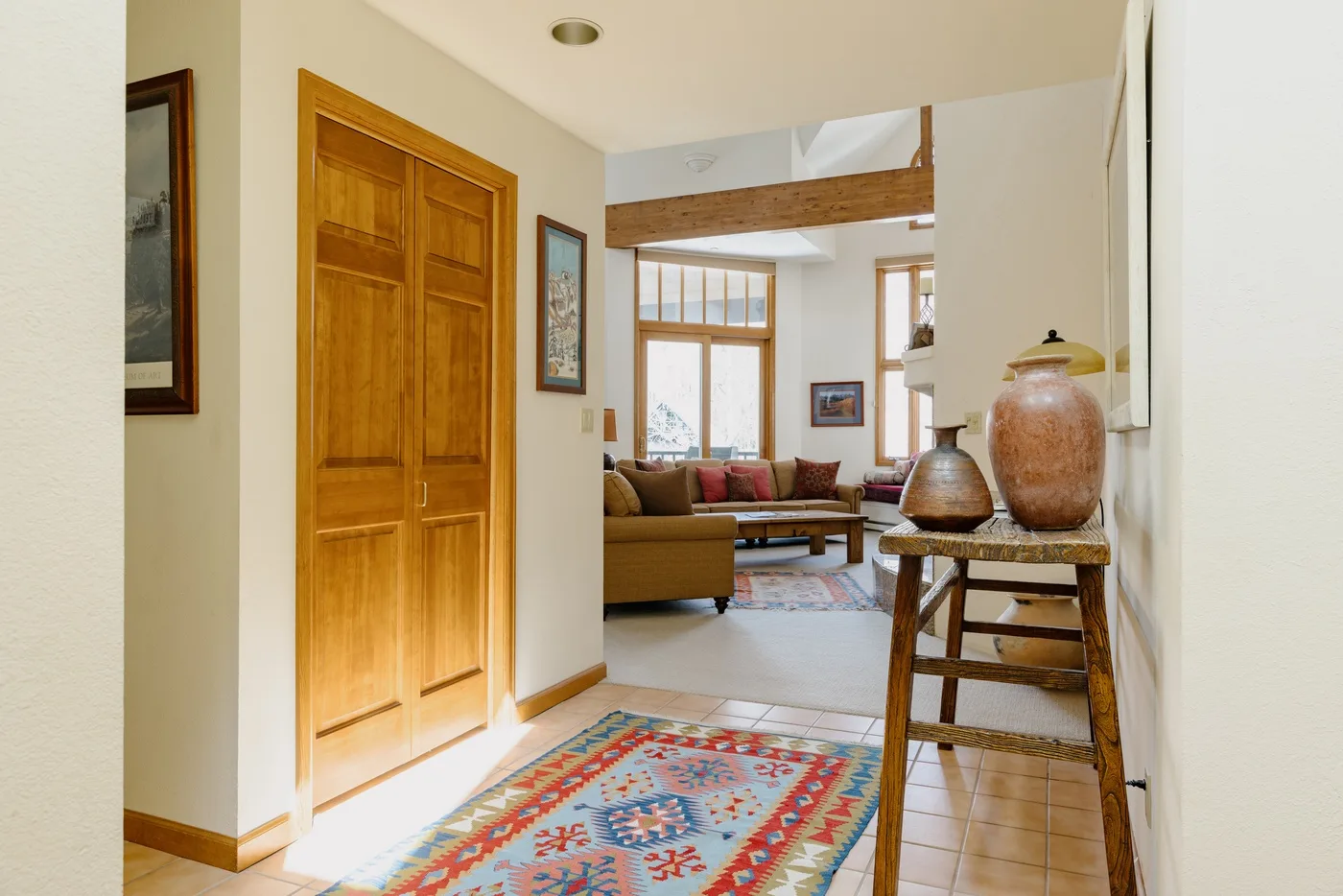 A hallway opens into a living room, with a patterned rug in the foreground.