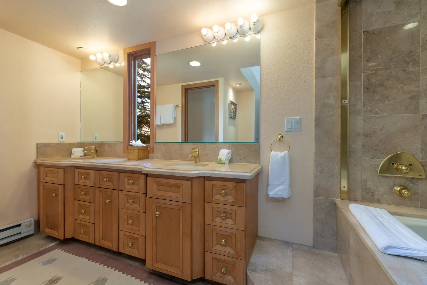 A bathroom vanity with a wide mirror sits beside a tiled shower area.
