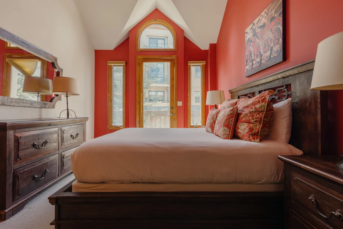 A bedroom with a bed, bedside tables, and tall windows.
