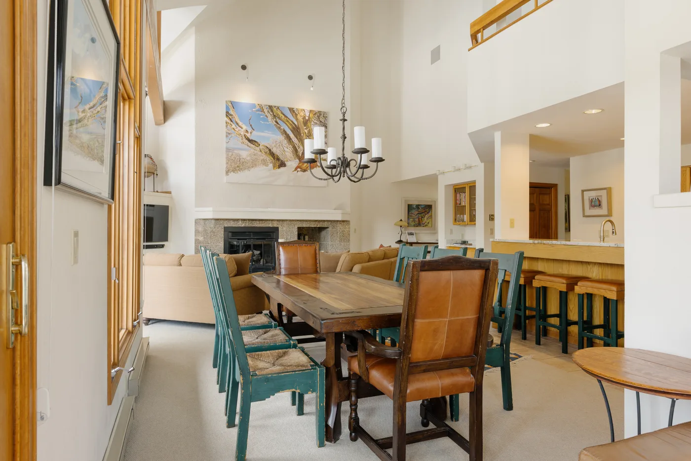 A double-height living and dining area with a long wooden table and fireplace.