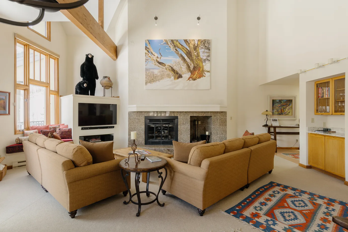 A spacious living room with seating arranged around a fireplace and television.