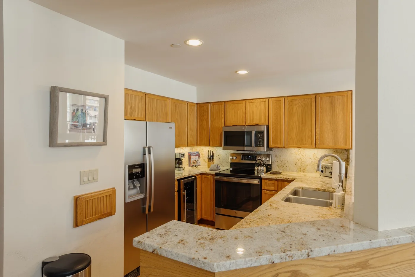 A kitchen with wooden cabinets, stainless steel appliances, and a stone countertop.