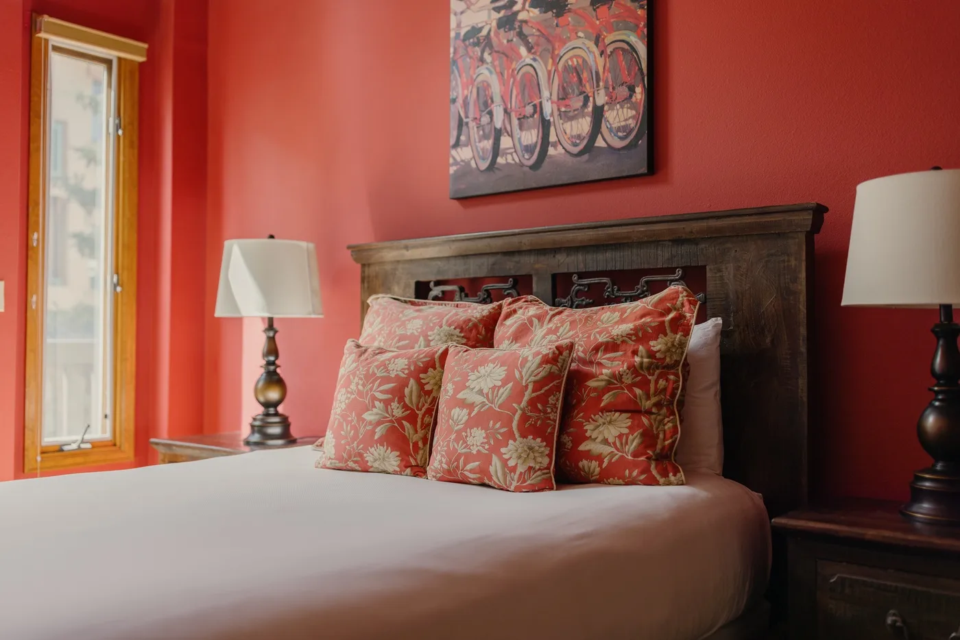 A bedroom with a bed, patterned pillows, and matching bedside lamps.