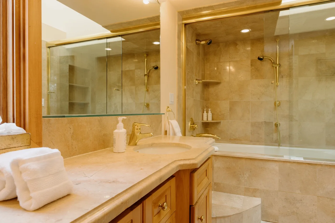 A bathroom vanity with a sink sits beside a glass-enclosed shower.