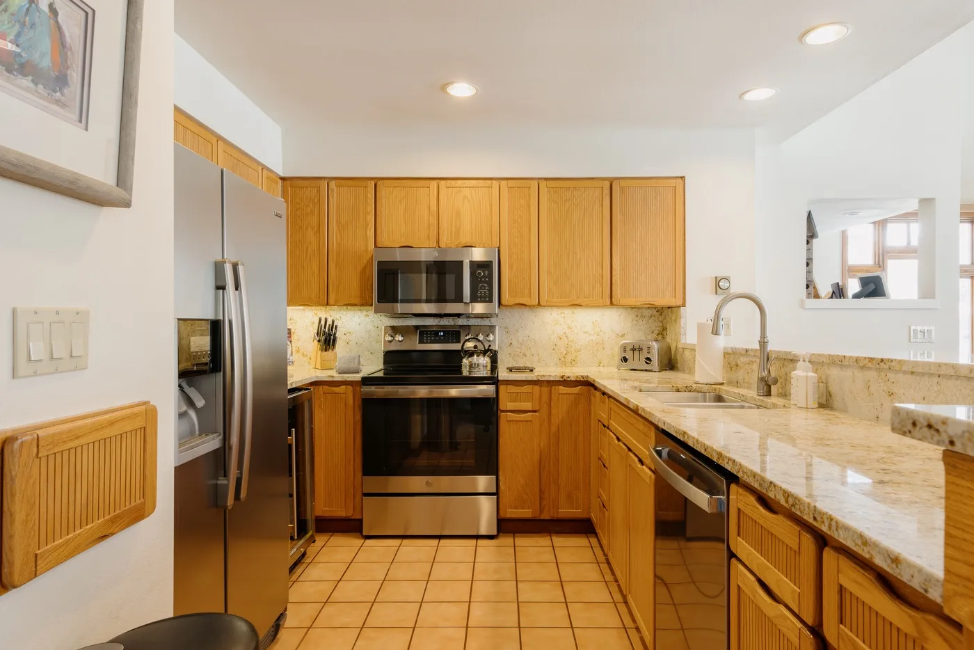 A kitchen with wooden cabinets, stainless steel appliances, and a long countertop.