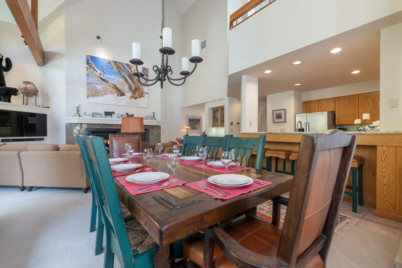 A dining area with a long wooden table set with dishes and turquoise chairs.