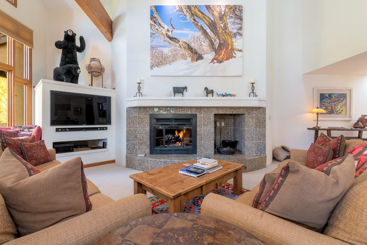 A living room with a stone fireplace and seating around a wooden coffee table.