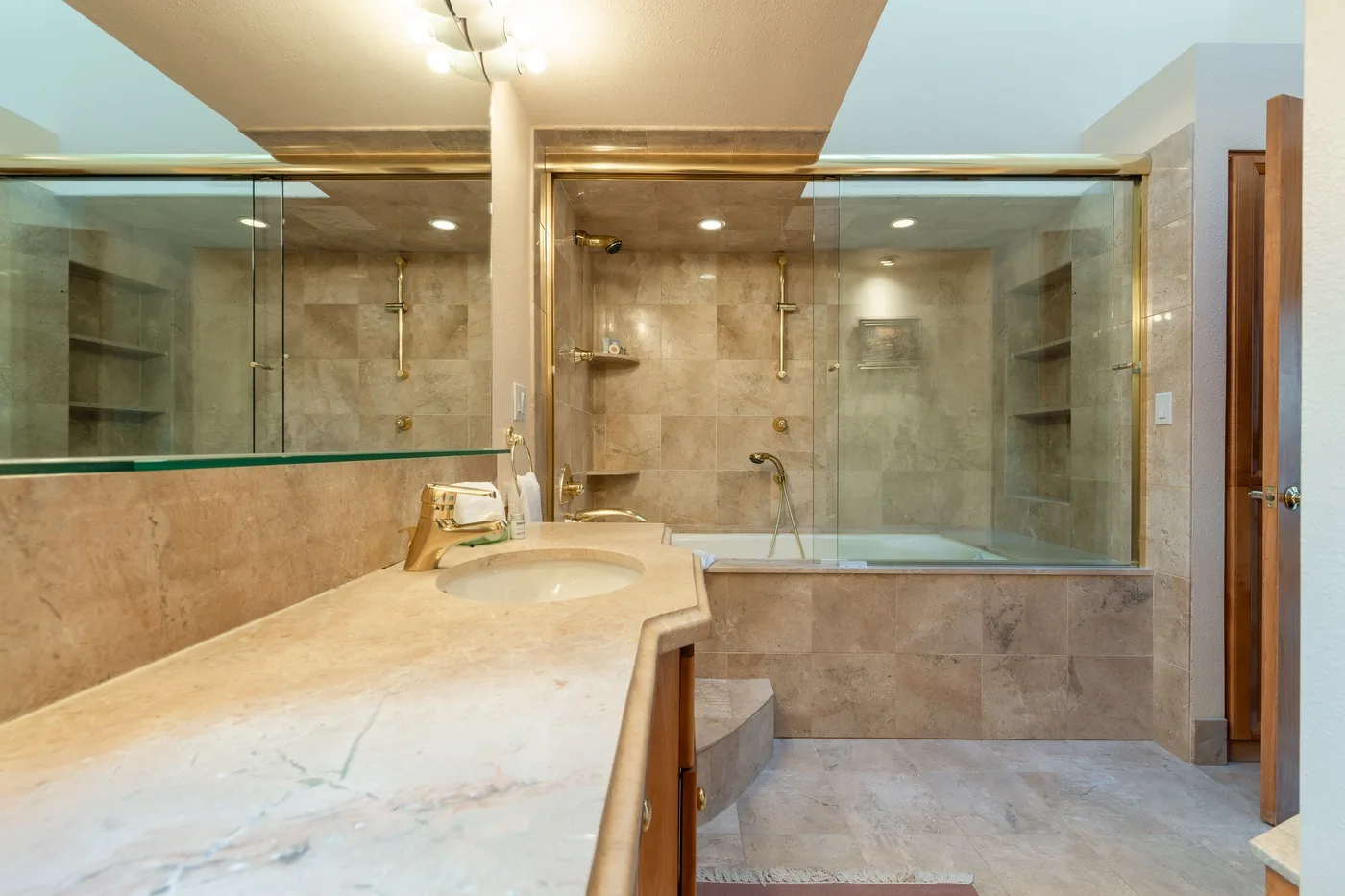A spacious bathroom with a long vanity and glass-enclosed shower area.