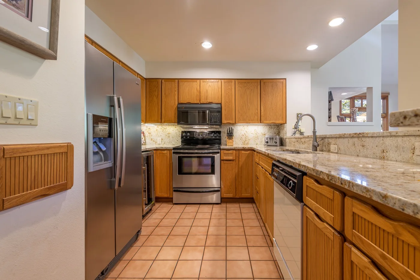 A kitchen with wooden cabinets, stainless steel appliances, and a tiled floor.