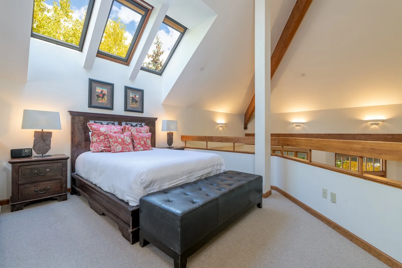 A bedroom with a bed beneath slanted skylight windows.