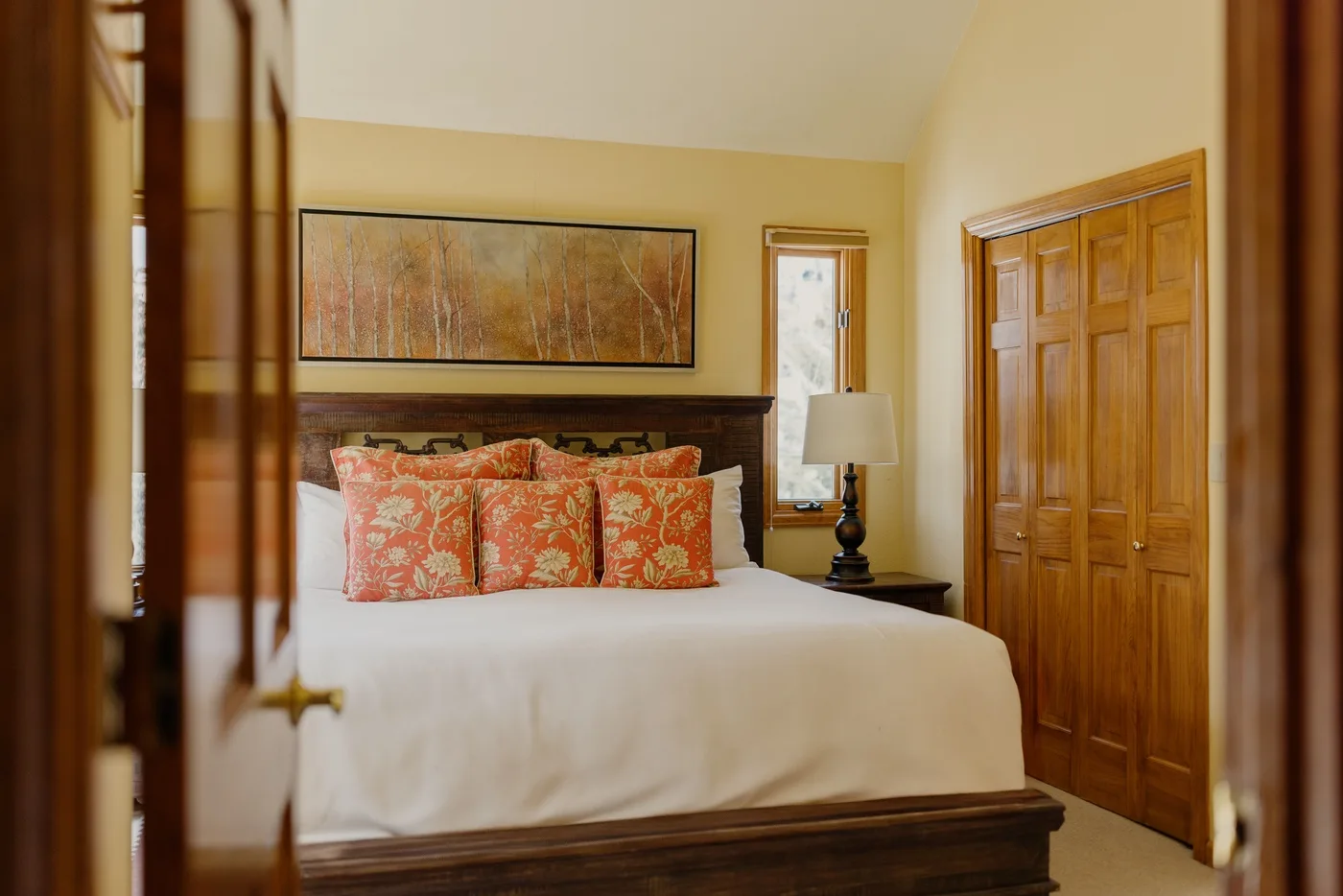 A bedroom with a neatly made bed and colorful patterned pillows.