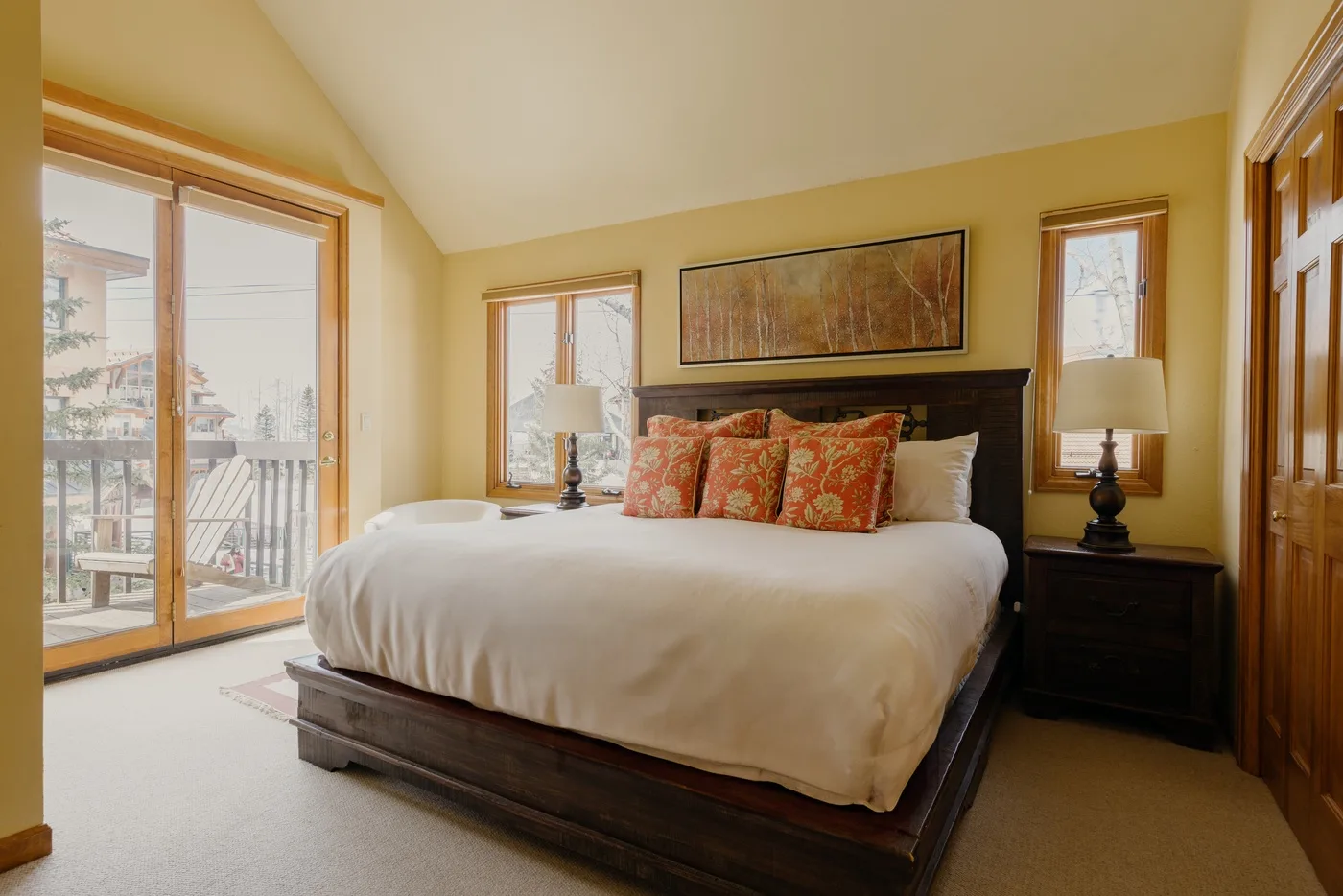 A bedroom with a large bed, decorative pillows, and a bedside lamp.